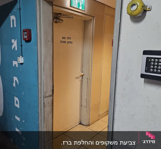 דלת יציאה עם שלט חירום על קיר כחול